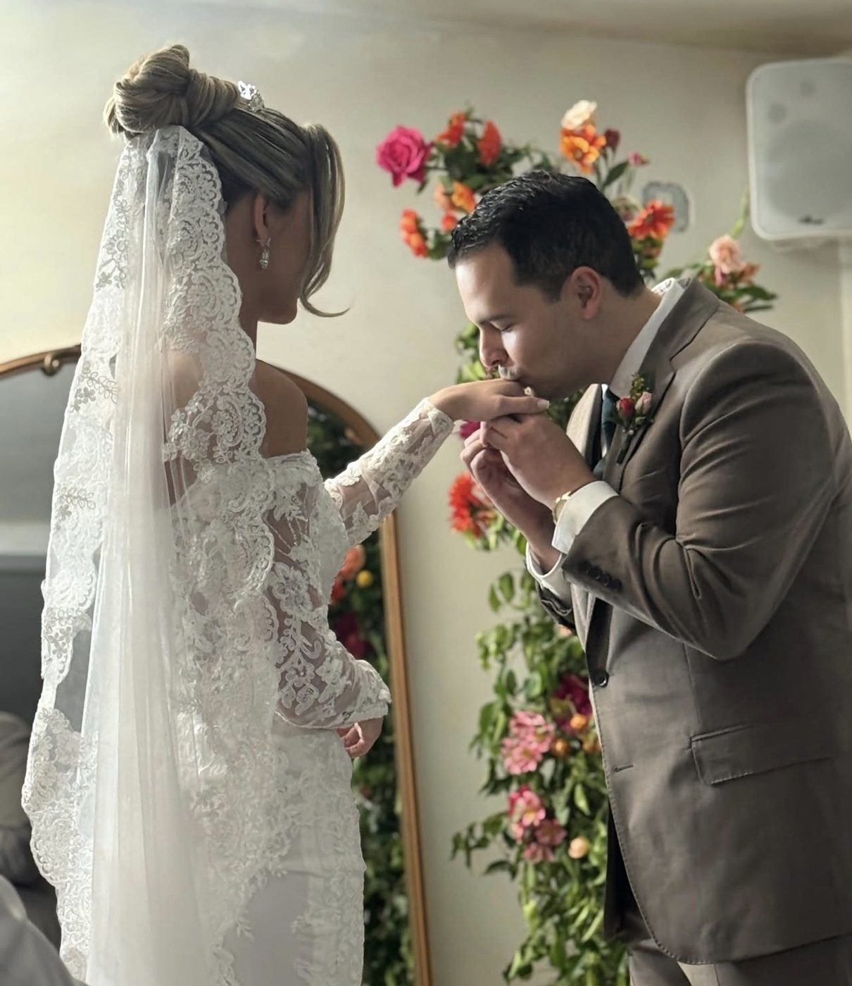 Bride and groom sharing a moment beside a floral wall at Sol Haus